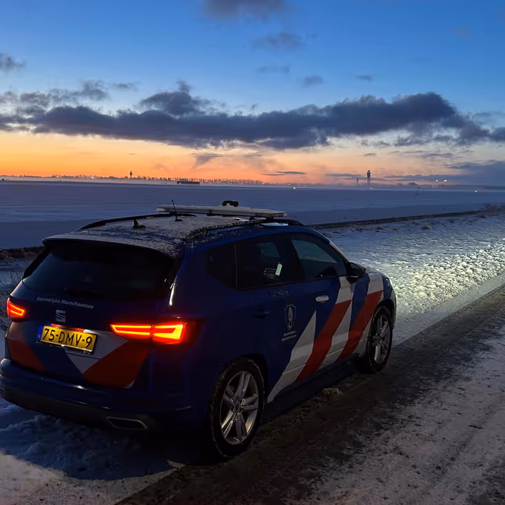 Voertuig van de Marechaussee voor besneeuwd Schiphol.