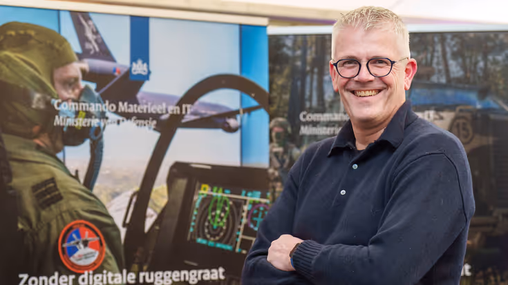 Man met armen over elkaar kijkt lachend in de camera.