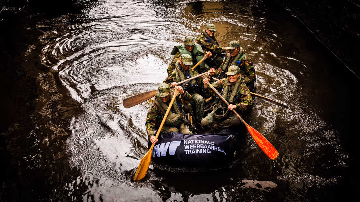 De deelnemers aan de NWT roeien in rubberboten door Amsterdam.