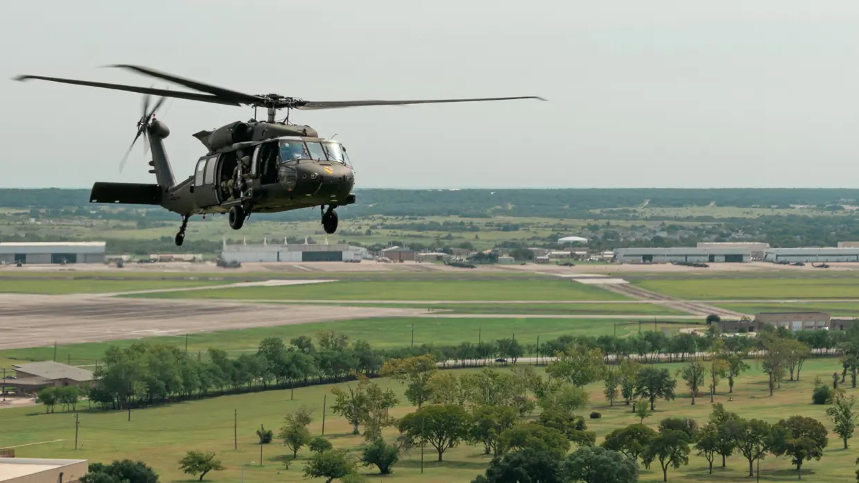 Amerikaanse Black Hawk vliegend boven gras, boven en Amerikaanse militaire gebouwen.