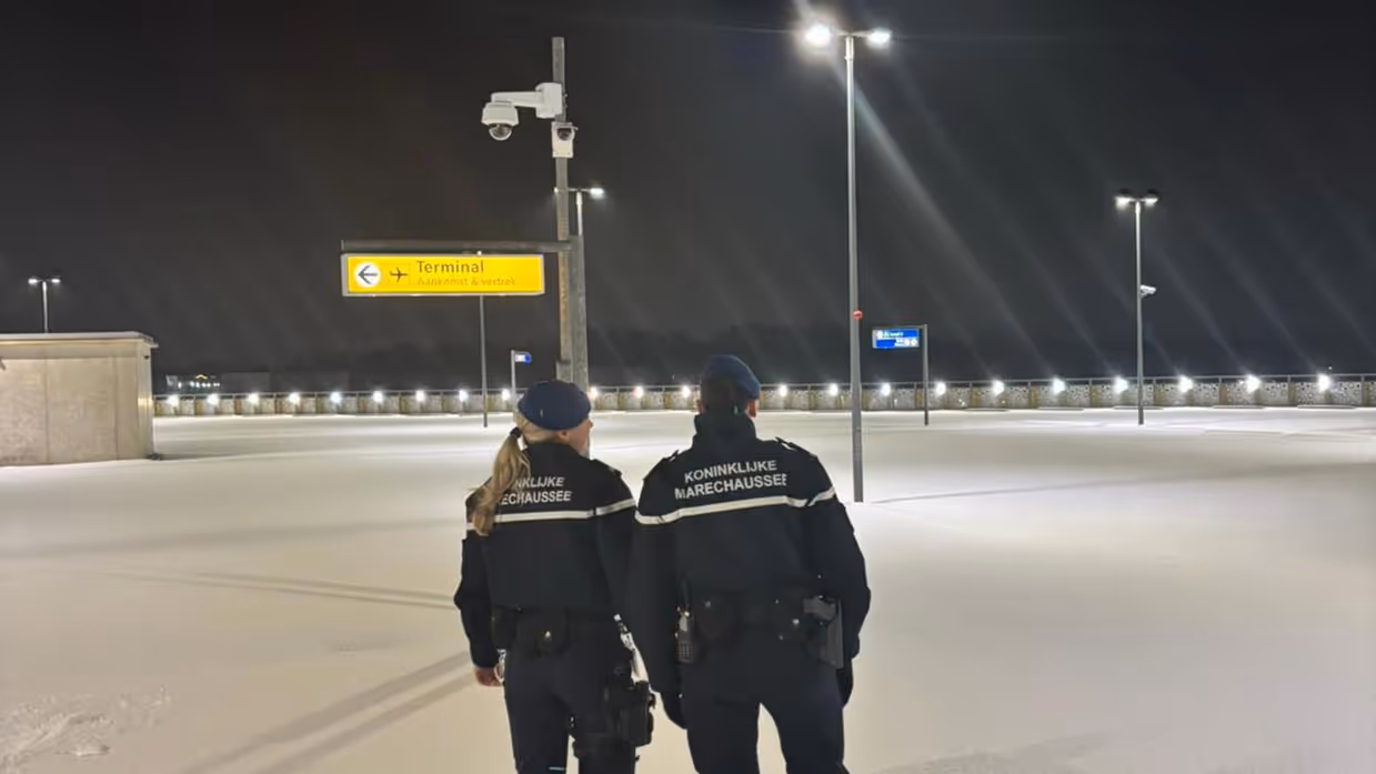 Marechaussees staan in dik pak sneeuw op luchthaven.