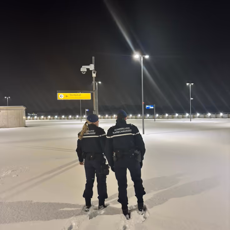 Marechaussees staan in dik pak sneeuw op luchthaven.