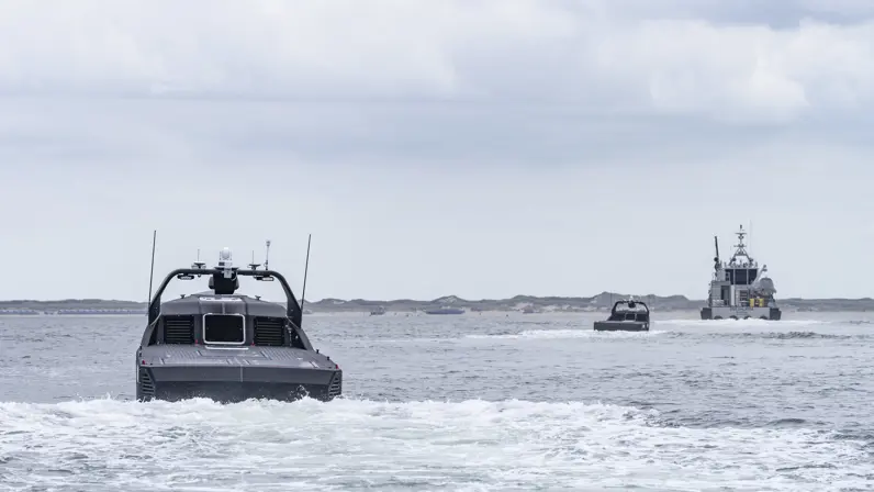 Twee onbemande boten varen op zee achter schip aan.