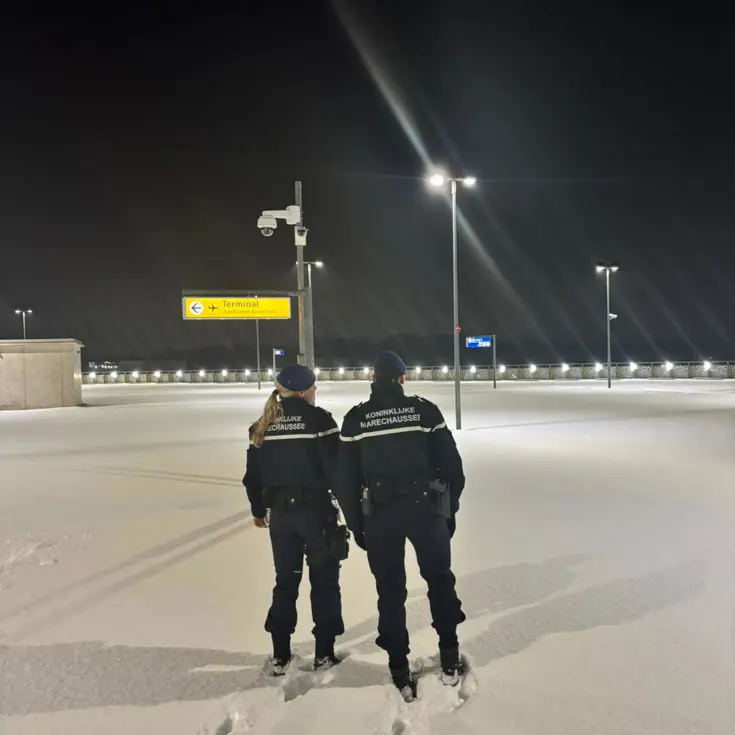 Marechaussees staan in dik pak sneeuw op luchthaven.