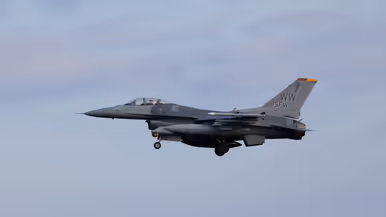 Een F-16 in de landing onder een blauwe lucht. 
