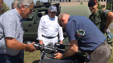  Een militair met een groot wapen wordt omringd door een aantal mensen.