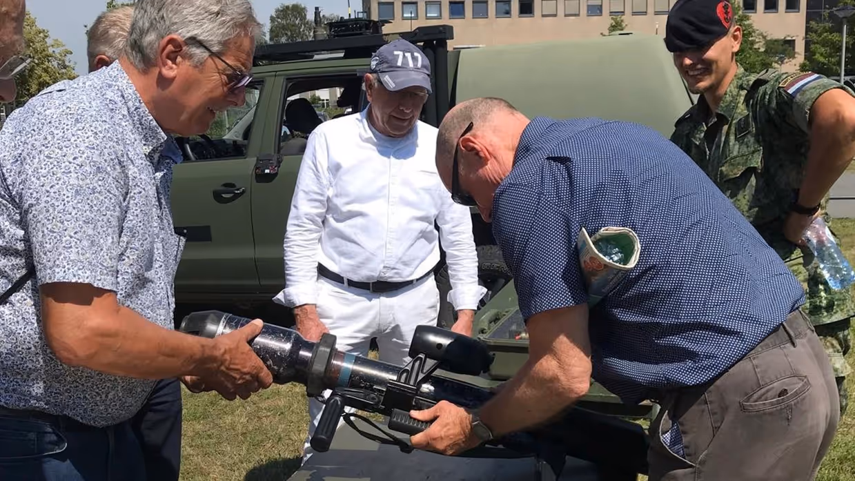  Een militair met een groot wapen wordt omringd door een aantal mensen.