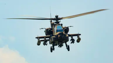 Een militaire helikopter van voren gezien onder een blauwe lucht.