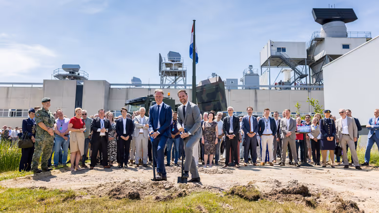 Twee mannen steken een schop in de grond. 