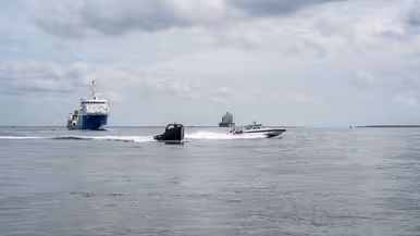2 kleine vaartuigen en 2 grote schepen varen in formatie.