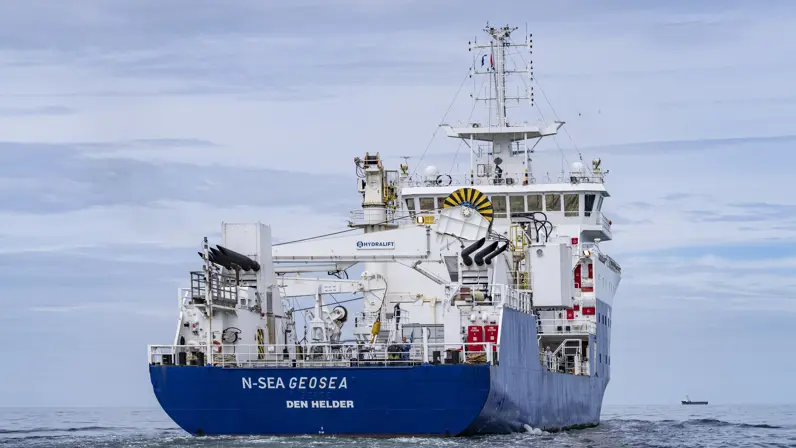 Achterkant van groot schip dat op zee vaart.
