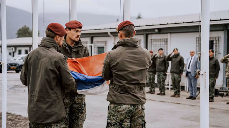 3 militairen vouwen de Nederlandse vlag op.