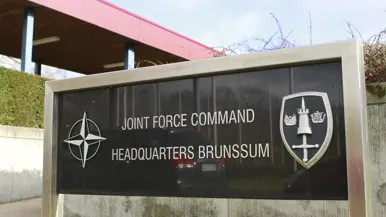 Een toegangsbord waarop de naam van het Joint Force Command Brunssum te lezen is. 