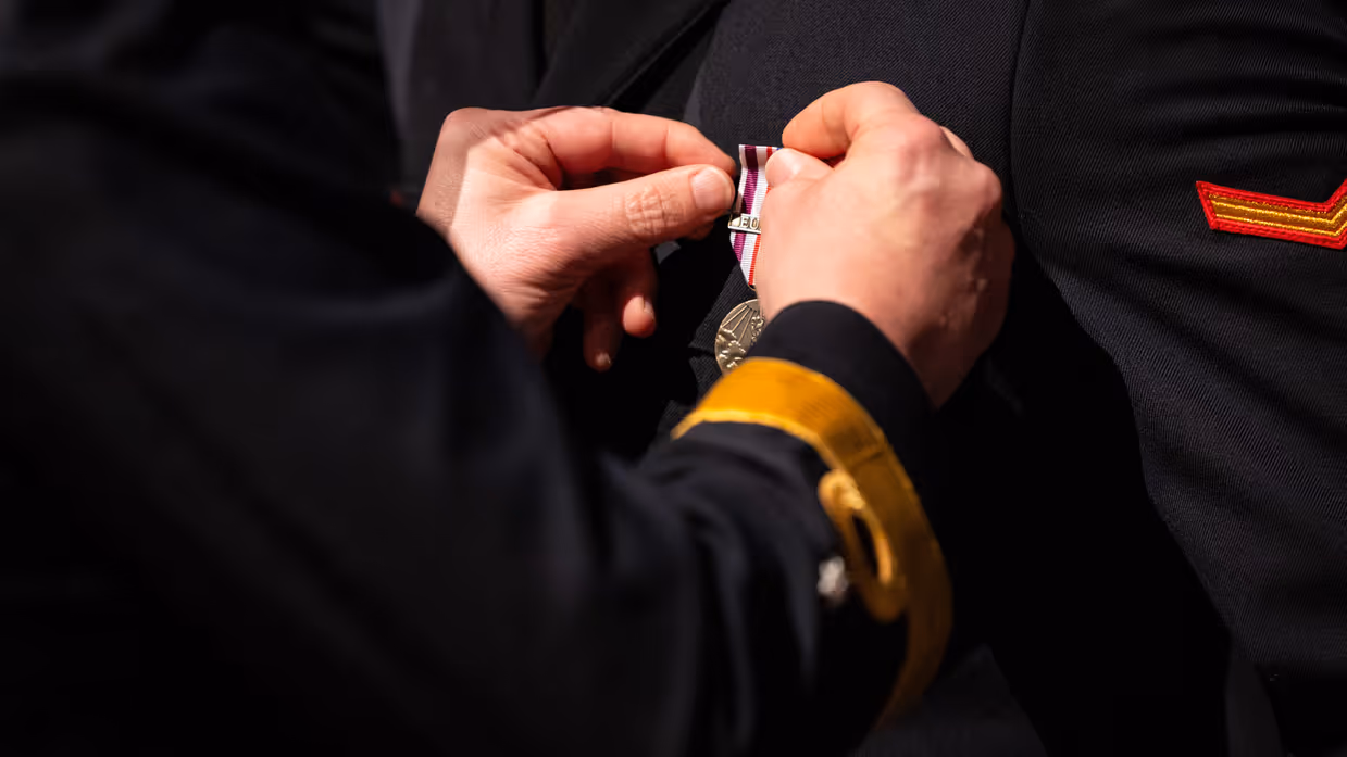 Close up van twee handen die medaille op revers militair spelden.