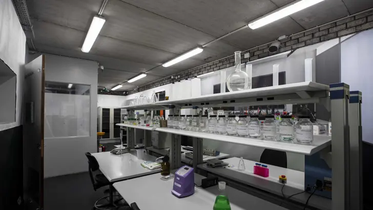 Ruimte met bureaus met daarop flesjes en potjes met chemicaliën.