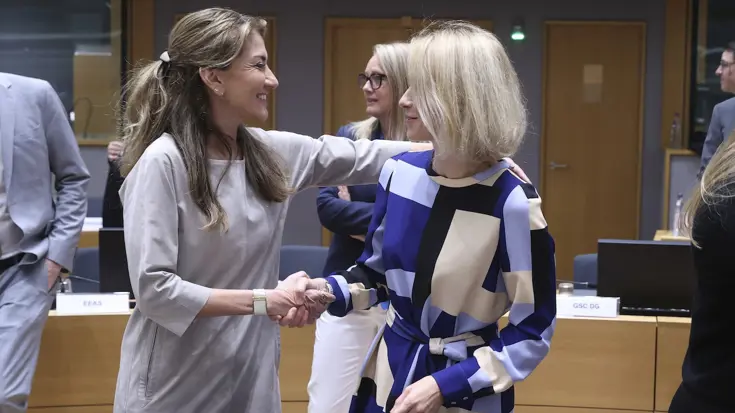 Twee vrouwelijke ministers schudden elkaar de hand.