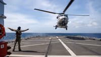 Helikopter landt met aanwijzing van militair op schip.