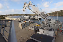 Hijskraan takelt container aan dek van schip.
