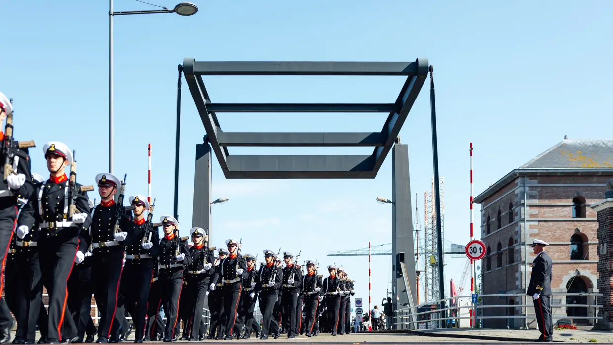 Rij marcherende militairen hebben net een brug gepasseerd.