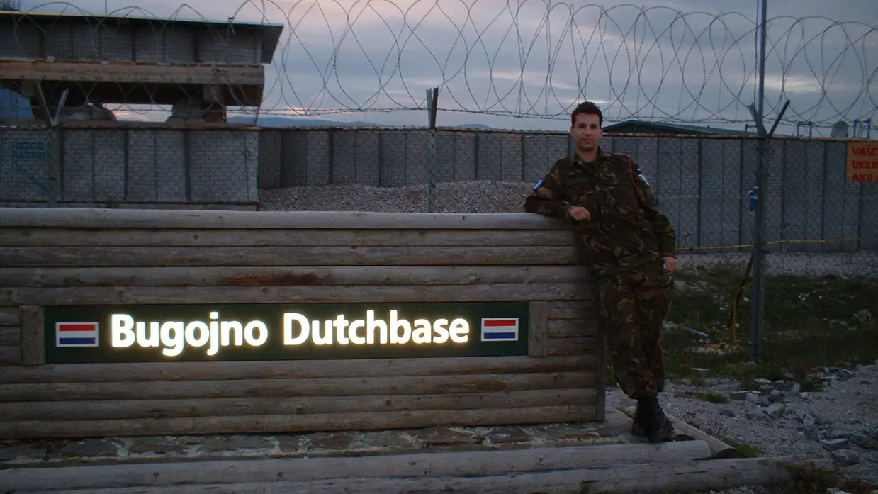 Een jonge Marcel Pelster poseert bij het bord bij de ingang van het kamp in Bosnië. Foto: uit privé-archief