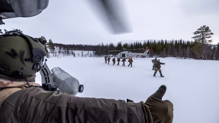 Militairen stappen uit helikopter in sneeuwlandschap.