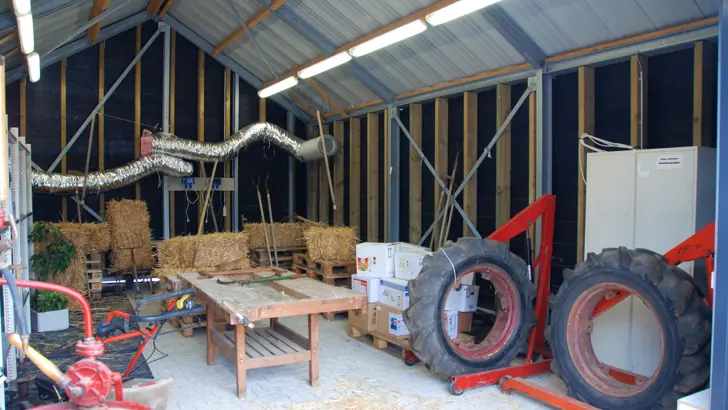 Loods met verschillend agrarisch materiaal, zoals strobalen en tractorwielen.