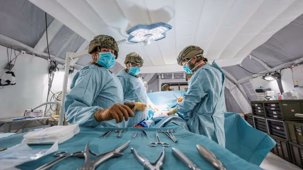 Leden van een chirurgisch team met helmen op en groene pakken aan. Op de voorgrond zilverkleurig medisch gereedschap.