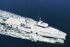 Wit patrouilleschip vaart met snelheid op donkerblauw water.
