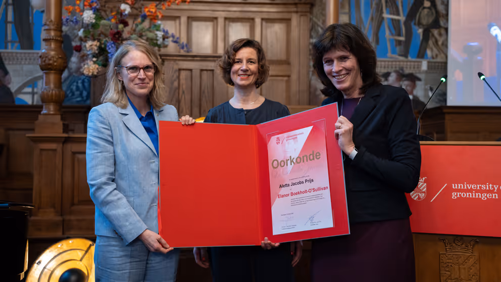 3 vrouwen houden een oorkonde vast.