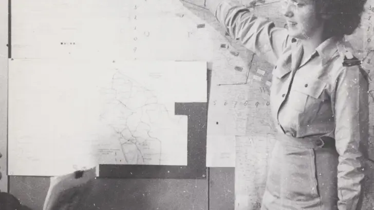 Een vrouwelijke militair wijst iets aan op een bord.