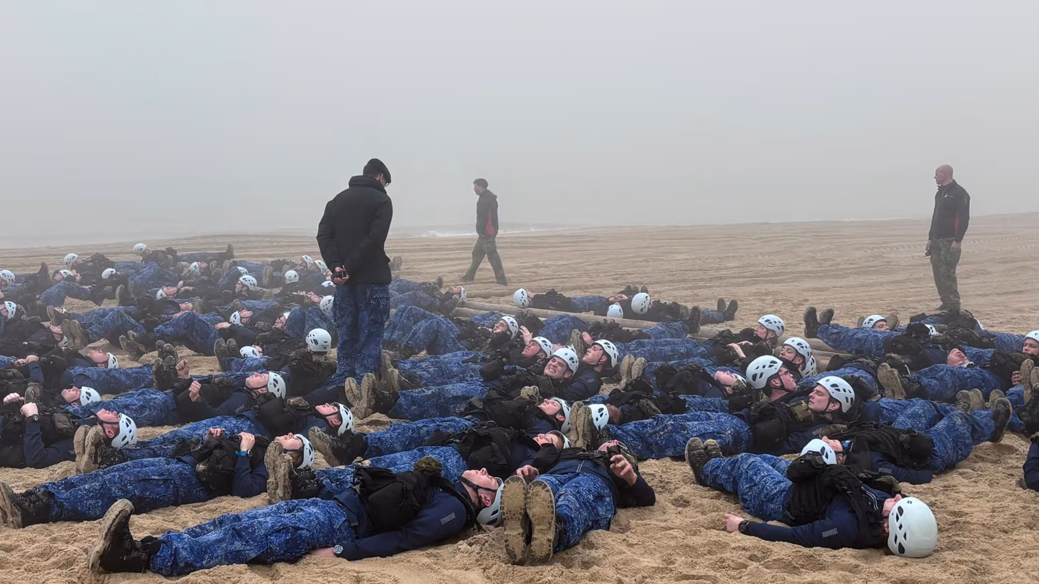 Matrozen in opleiding liggen op het strand, klaar voor sit-ups