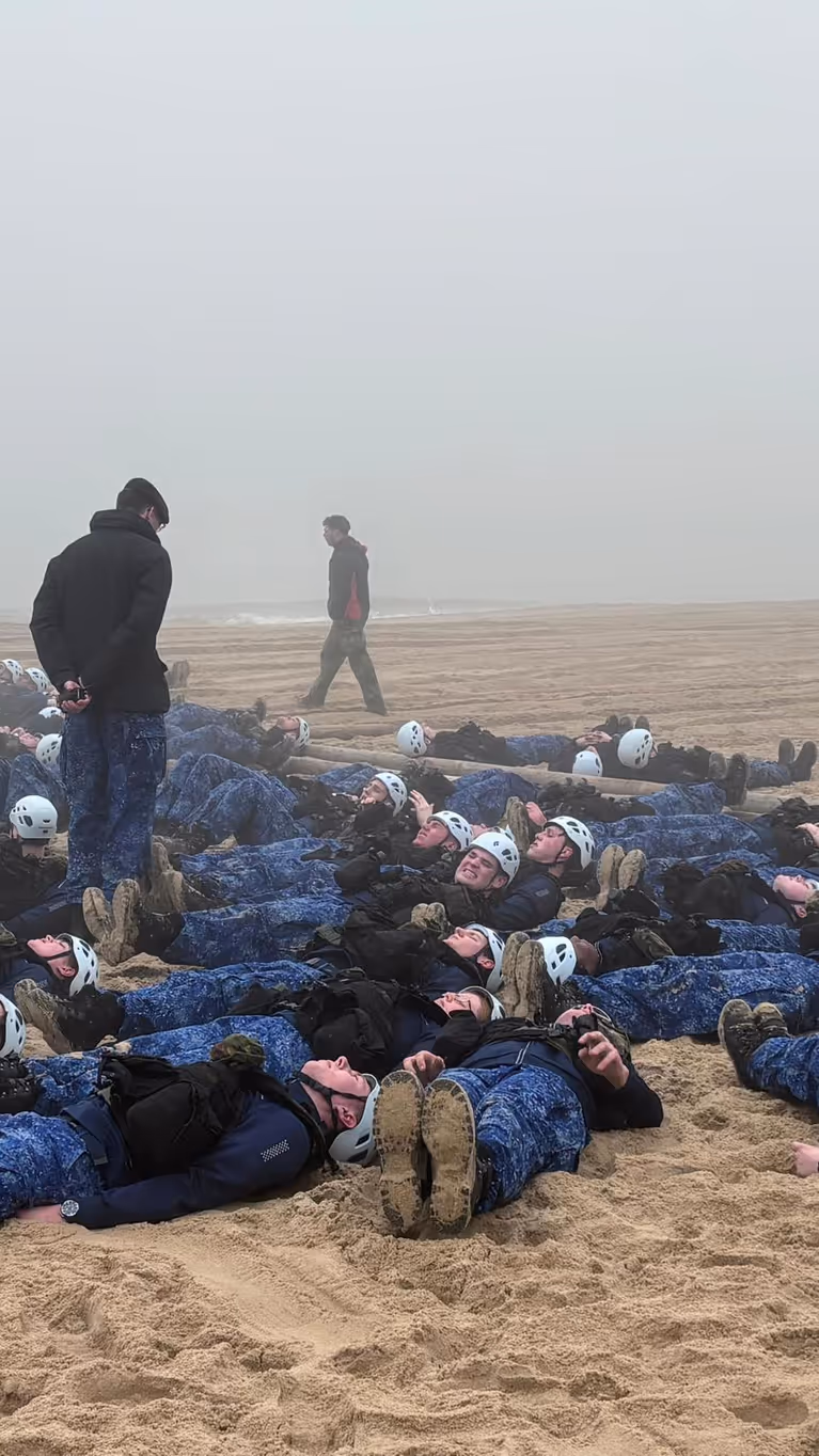 Matrozen in opleiding liggen op het strand, klaar voor sit-ups