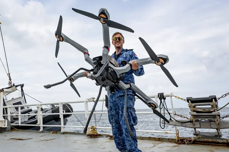 Man met drone op het dek van een schip
