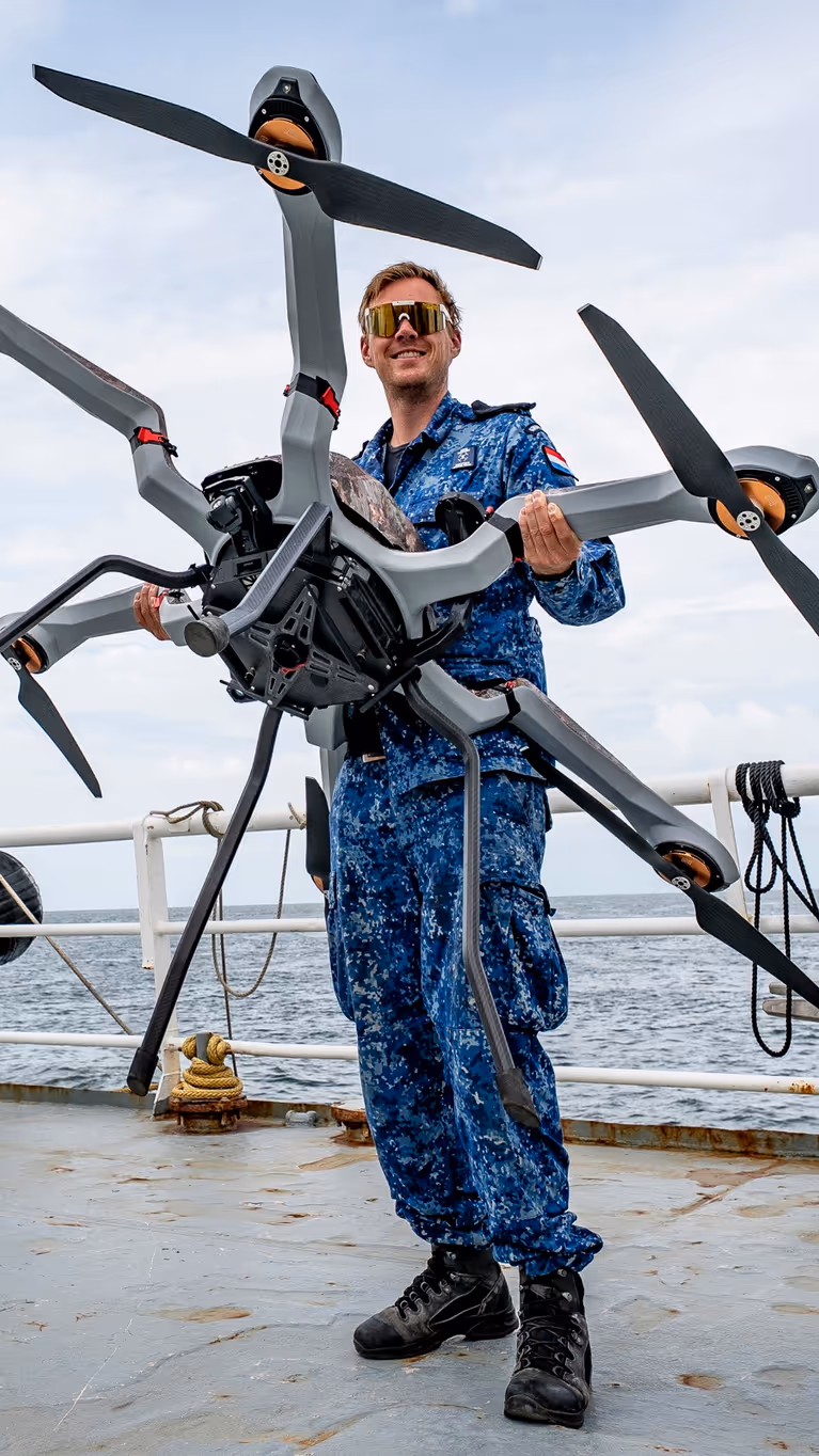 Man met drone op het dek van een schip