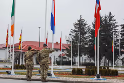 2 Nederlandse militairen salueren voor een rij vlaggen.