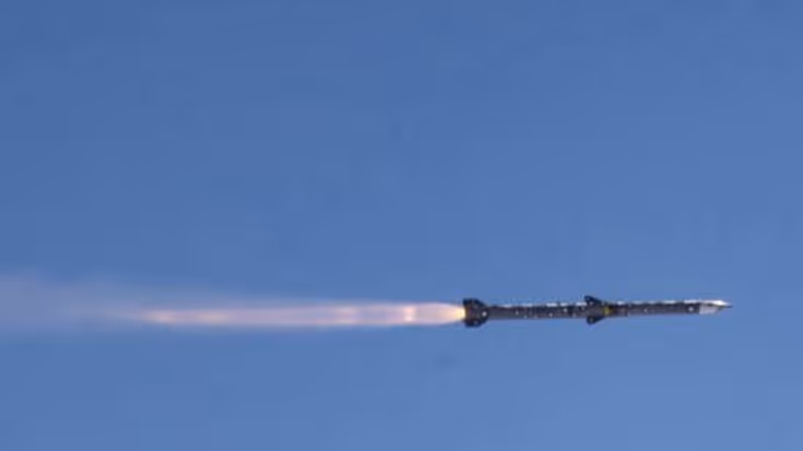 Een vliegende Amraam-raket vanaf de zijkant gezien, met rookpluim erachteraan.