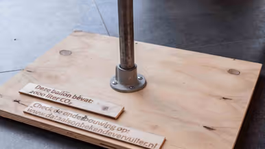 Een houten onderzetter met stalen tafelpoot.