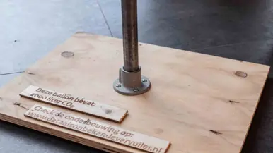 Een houten onderzetter met stalen tafelpoot.