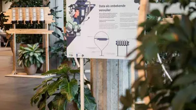 Informatieborden tussen plantenbakken in een hal.