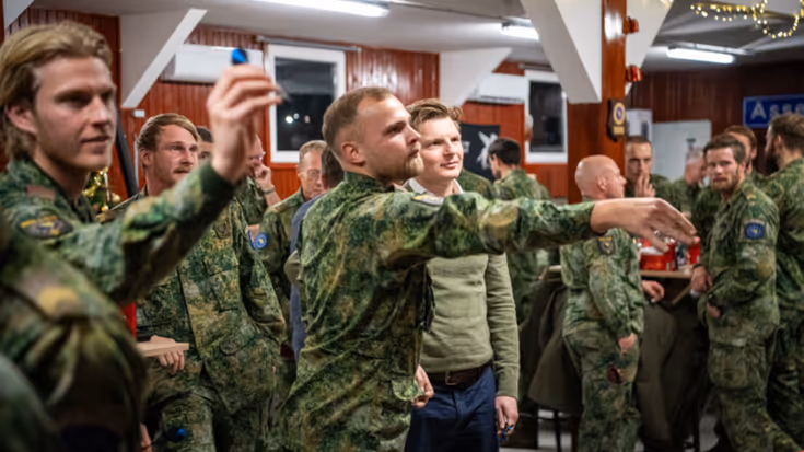 2 militairen in uniform gooien ongeveer tegelijkertijd een dartpijltje het beeld uit.