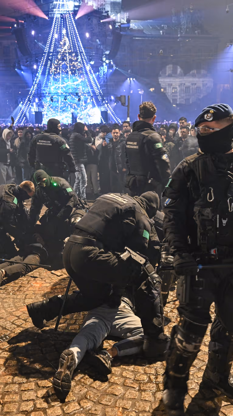 Voertuigen van de ME en politie met mannen met schilden ervoor.