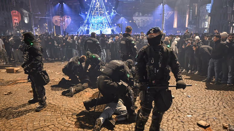 Voertuigen van de ME en politie met mannen met schilden ervoor.