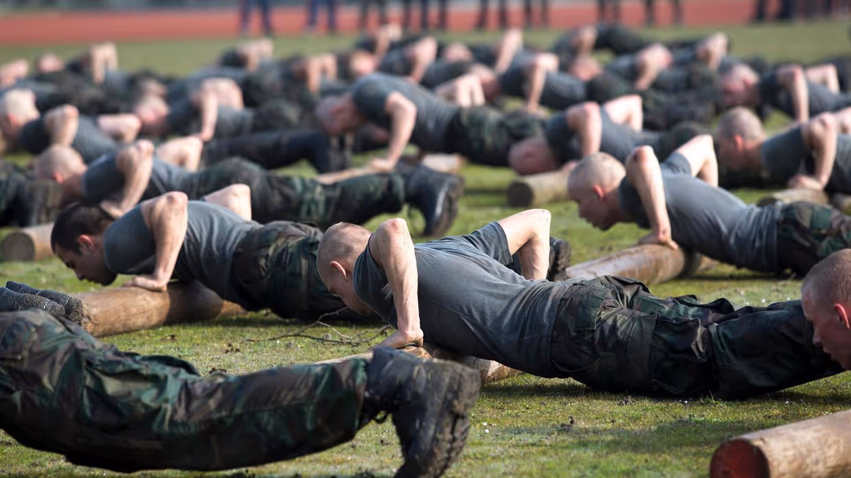 Groep militairen is aan het opdrukken in het gras.