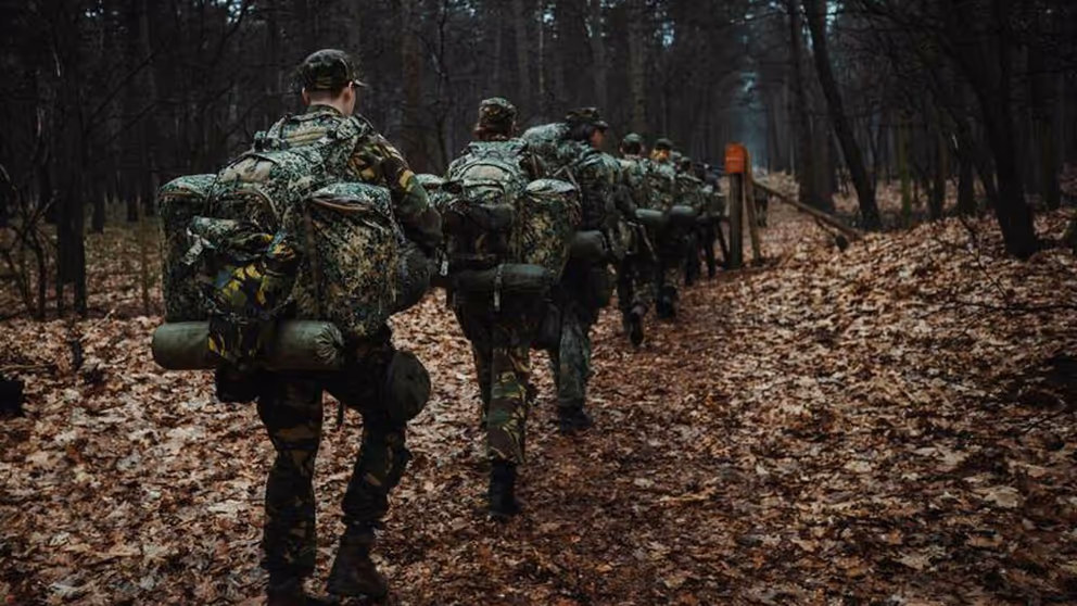 Reservisten lopen met bepakking door een bos.