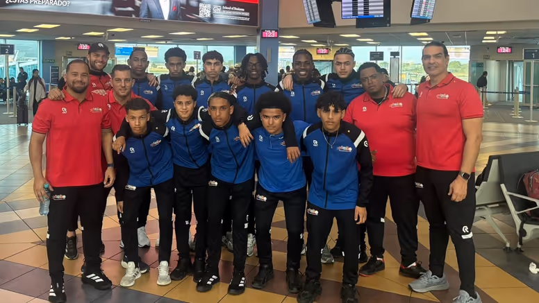 Een elftalfoto met spelers, trainers en coaches op de luchthaven. 