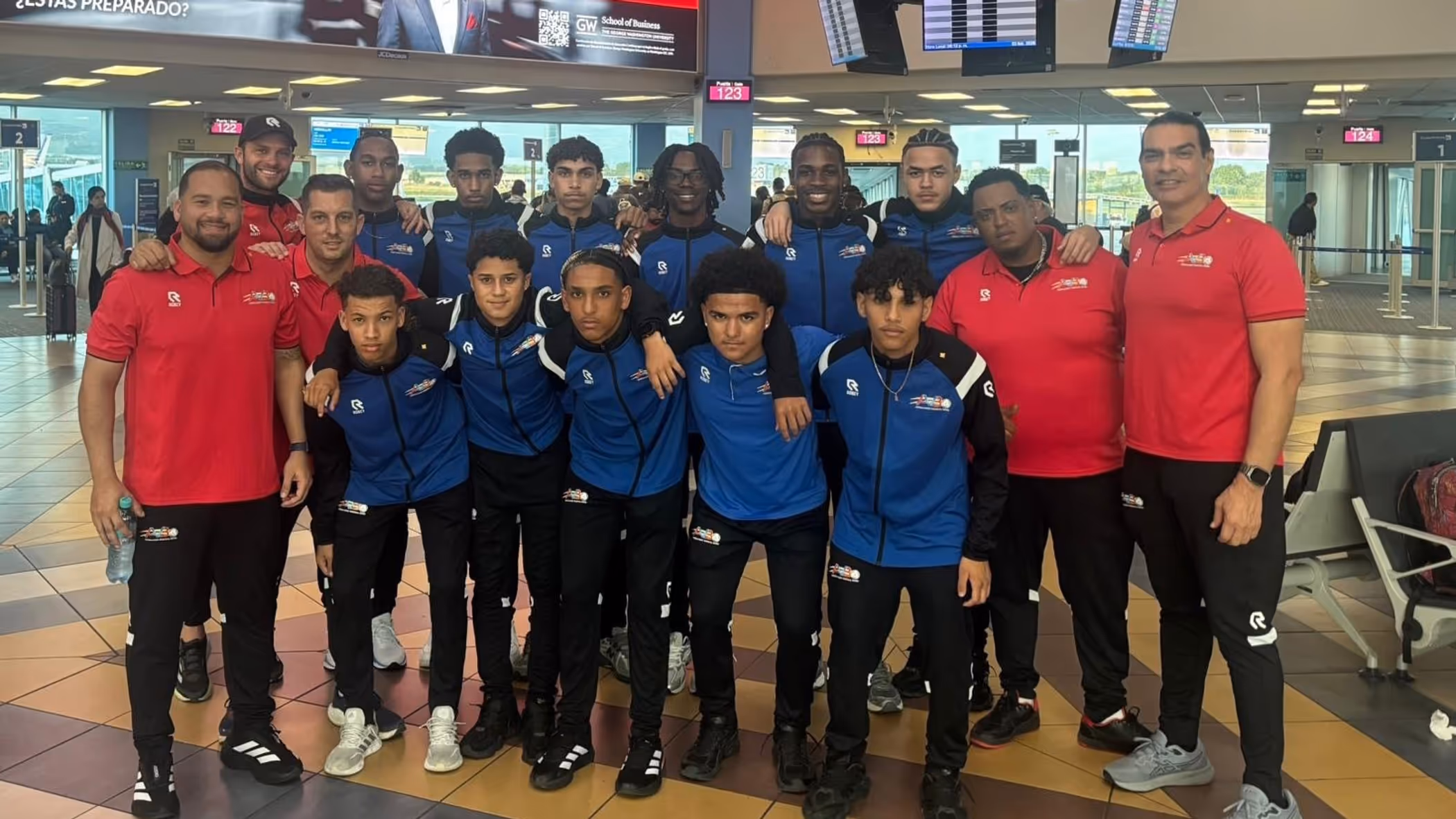 Een elftalfoto met spelers, trainers en coaches op de luchthaven. 