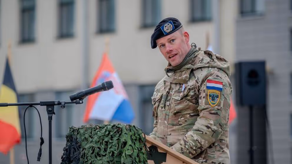 Militair in uniform houdt toespraak achter katheder.