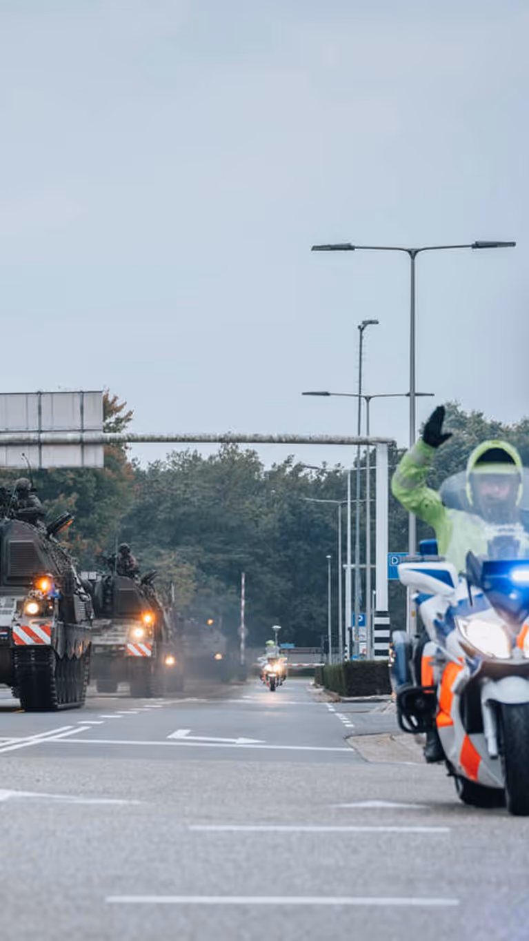 Een motor van de Marechaussee met op de achtergrond voertuigen van de Landmacht.