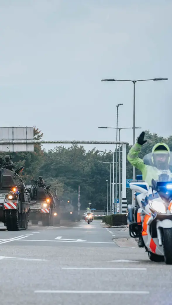Een motor van de Marechaussee met op de achtergrond voertuigen van de Landmacht.