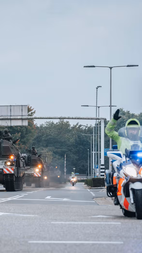 Een motor van de Marechaussee met op de achtergrond voertuigen van de Landmacht.